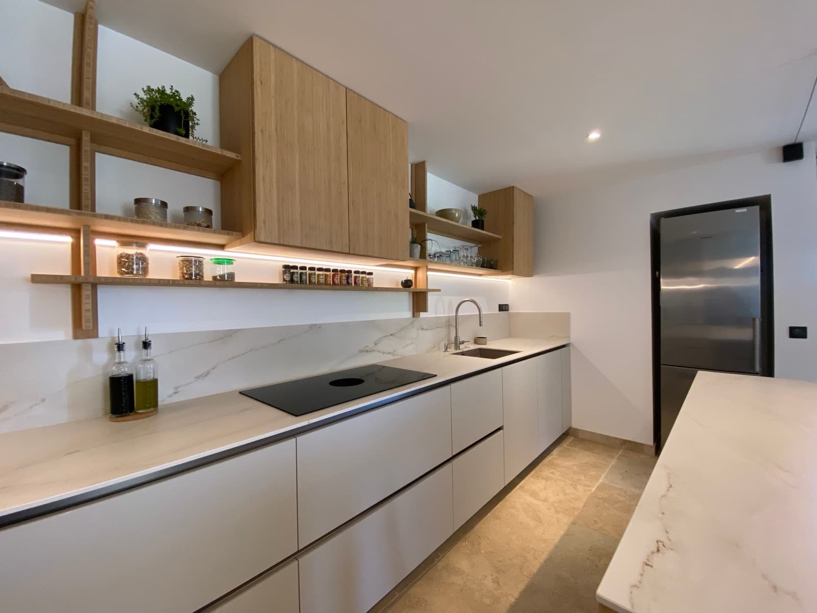 Gerenoveerde keuken met witte fronten, houten kasten en marmerlook achterwand
