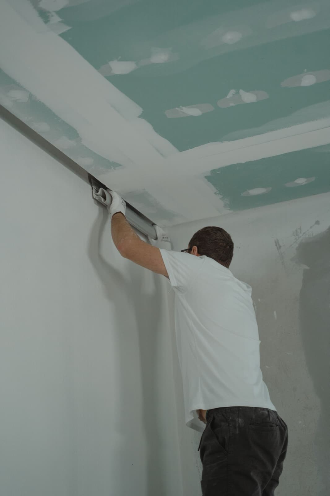 Stukadoor werkt de naad tussen wand en plafond glad af