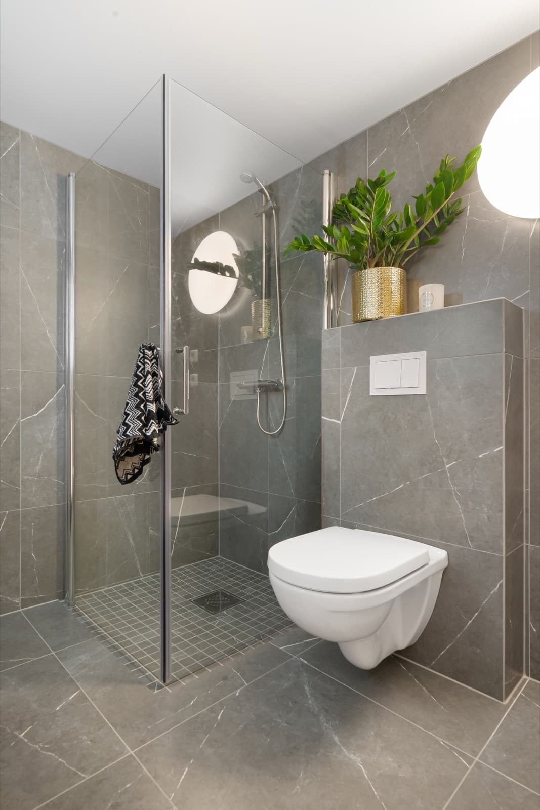 Douchehoek met glazen wand en zwevend toilet na renovatie