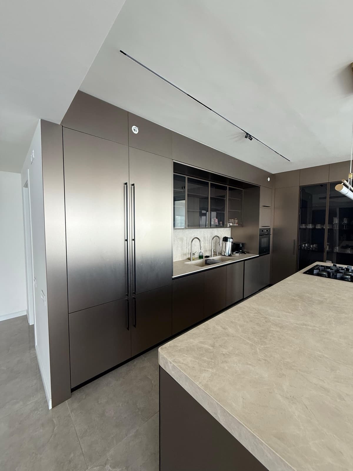 Moderne keuken in bronstinten met kookeiland en natuursteenlook werkblad