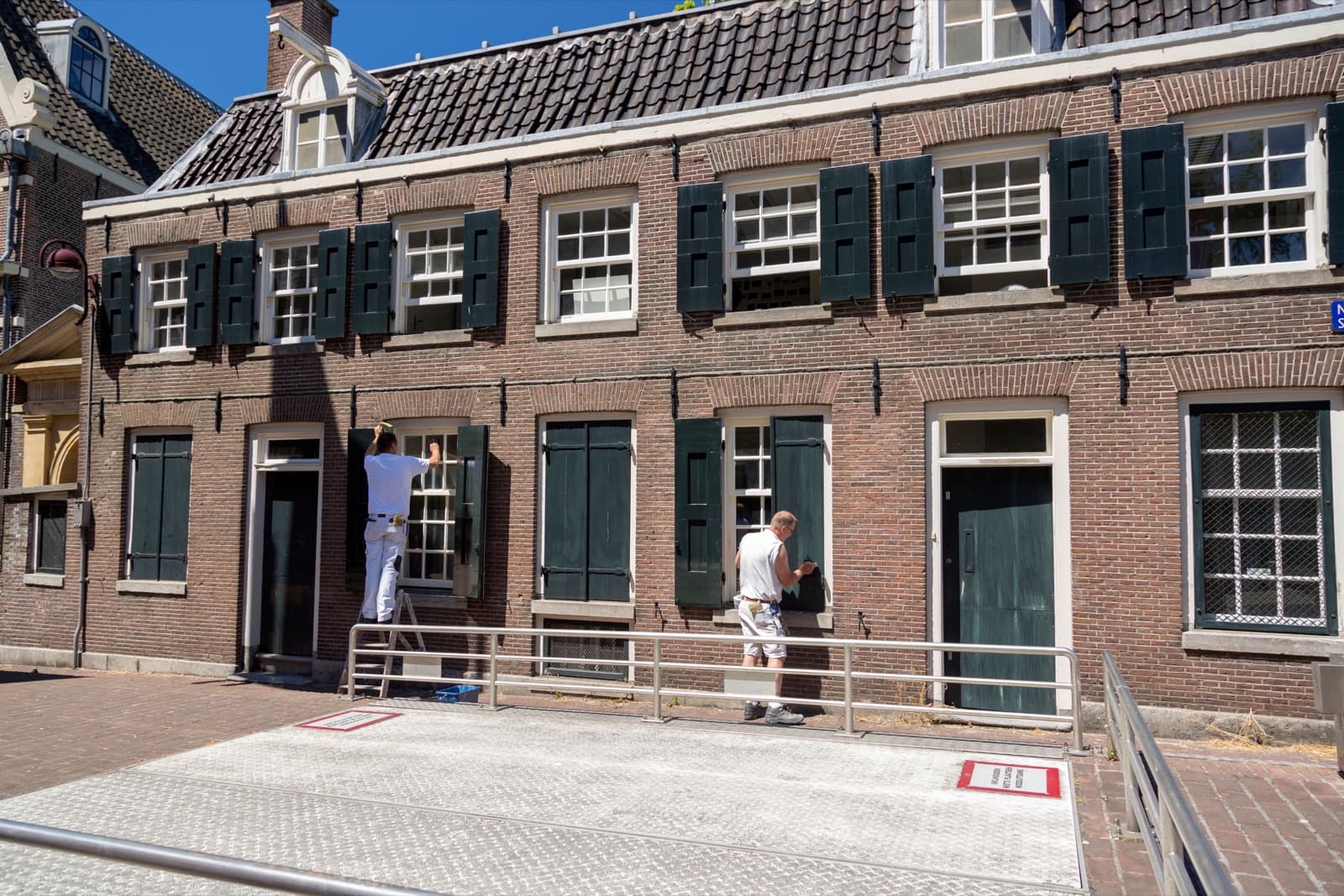 Schilders werken buiten aan de kozijnen en luiken van een woning